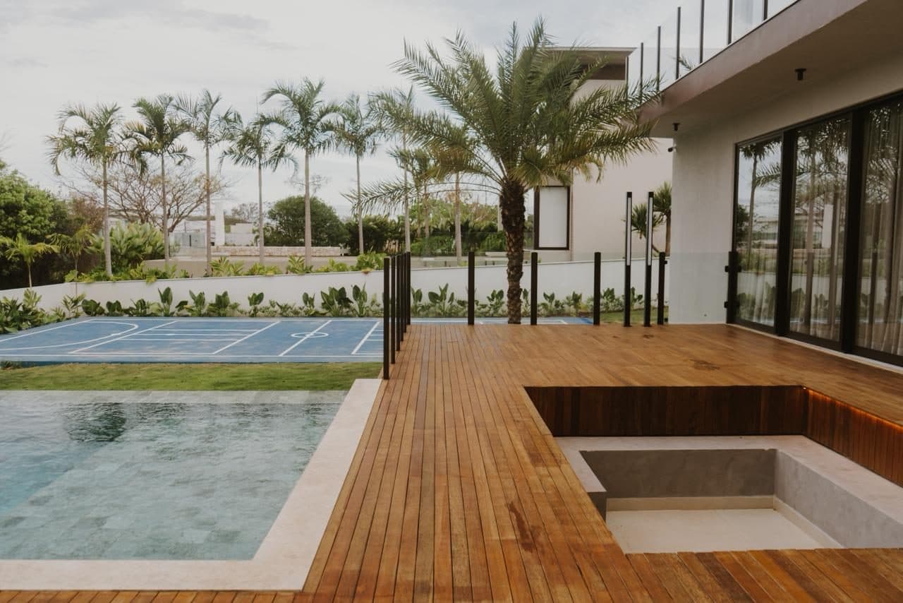 Deck à beira da piscina com jardim, palmeiras e lounge rebaixado integrado