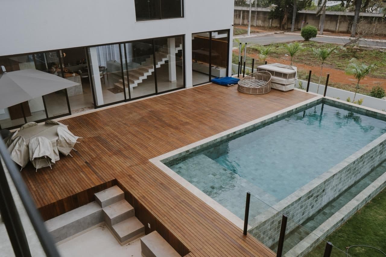 Vista superior de terraço com piscina, deck de madeira, portas de vidro e estar externo